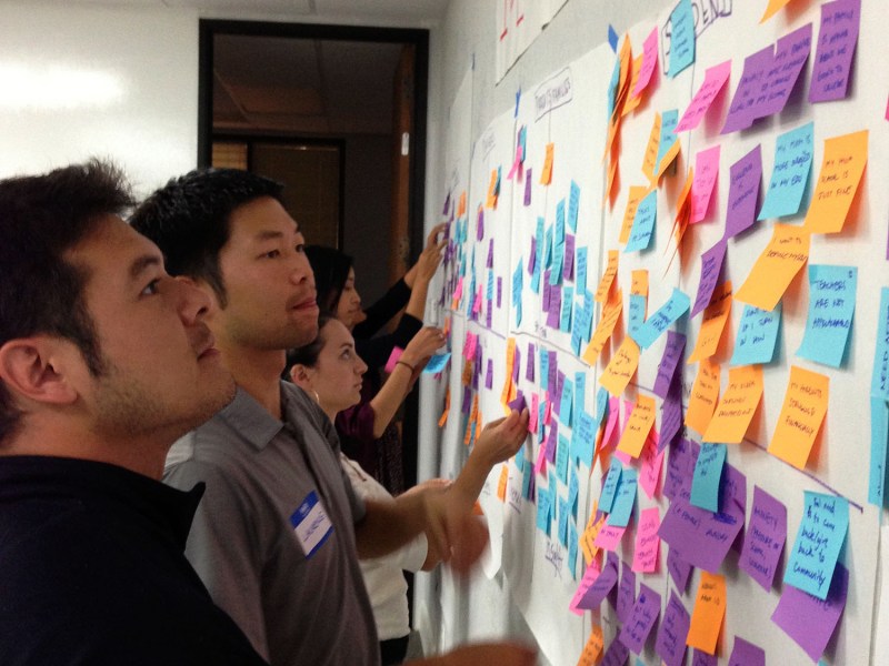 High School design team members check out ideas written on post-it notes during a brainstorming session.