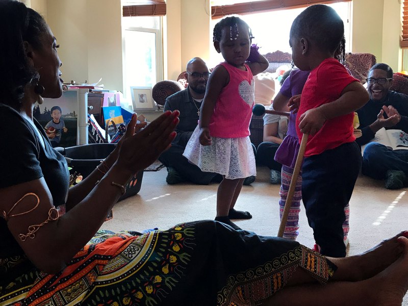 Maikko, 2, in pink, Terrance, 1, in red, and Nailah, behind Terrance, dance as their child care provider, Lorna Parks, foreground, claps during a visit by staffers from Detroit's African-American History Museum.